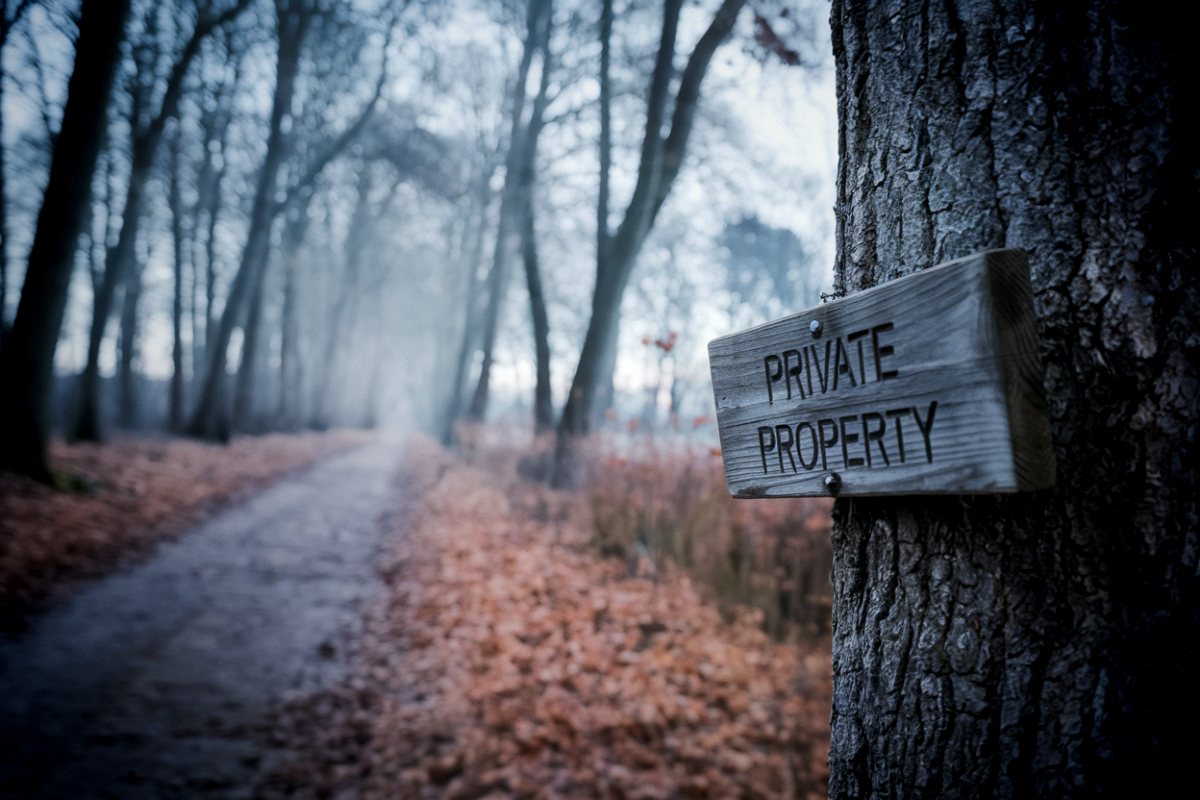 Forêts engrillagées : ce que la loi de février 2023 a changé pour votre droit de cheminer Un panneau propriété privée cloué sur un arbre en lisière d'une forêt privée française bordée d'un sentier